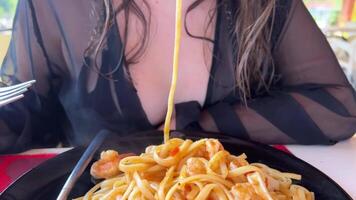 young teenage girl with wet hair eats spaghetti pasta pull spaghetti ocean pasta Carbonara with seafood sit on the beach in a restaurant Tanned face with freckles lick delicious food lunch video