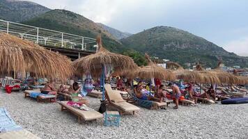 strand in de dorp van borsh in Albanië Doorzichtig lucht vakantiegangers mensen mooi zee Ionische zee pittoreske strand hutten langs de Albanië riviera vroeg in de ochtend- gedurende een mooi zomers dag video
