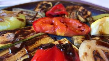 gegrillt bunt Gemüse Glocke Pfeffer, Zucchini, Aubergine auf ein Teller Über Licht grau Schiefer, Stein oder Beton Hintergrund. oben Aussicht mit Kopieren Raum. video