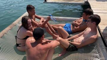 teenagers' vacation on the Ionian Sea Albania adolescence friends lie on a hammock over the river sea jump into the water tumble communication one girl and four guys Albania Ksamil video