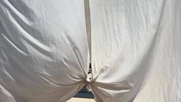 alt schmutzig Weiß zerrissen Tüll Vorhänge auf ein Sonnenbank in der Nähe von das Ozean das Meer entwickelt das Wind segeln Vorhänge auf Ferien auf das Strand video