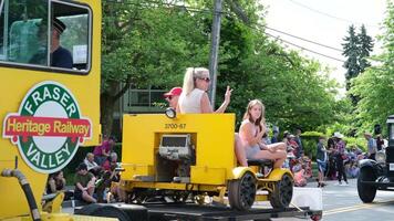 Cloverdale yellow tractor truck at the gay pride parade in the city of Surrey people waving their hands children sitting rest joy of communication village highway movement many spectators Canada 09.09 video