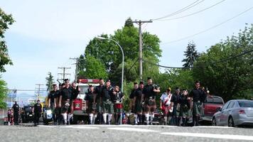 elderly men in Scottish skirts with bagpipes marching down the street during a gay pride parade drumming fire truck playing music drumming long knee socks outfit national dress of Scotland Cloverdale video