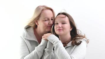 love of daughter and mother hugging kisses tenderness girl kisses her mother's hands mother hugs kisses her daughter on the cheek two women on a light background a lot of tenderness and joy of love video