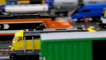 Spielzeug Zug Bahnhof ein schnell Beschleunigen Fracht Zug Nächster zu andere Wagen Stehen auf das Schienen ein schön Lego Konstrukteur Spiel ein Ausstellung Nahansicht gegen das Hintergrund von Häuser gebaut durch Menschen video