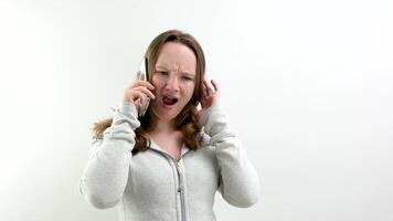 överraskning av en Tonårs flicka öppen henne mun talande på de telefon lyssna stänga öra behöver till höra är den verkligen på en vit studio bakgrund överraskning ett obehaglig överraskning video