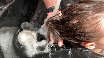 en man frisör tvättar kvinnas hår efter färgning henne hår. närbild video