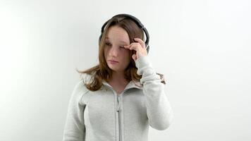 coçar olhos alérgico reação adolescente menina vestindo fones de ouvido em branco fundo antes arranhões dela testa e esfrega dela olho doença cobiçado frio necessidades para trabalhos tiroteio uma grampo fadiga video