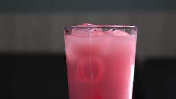 Strawberry milk in a glass with striped paper straw isolated on a black background video