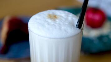 Nahansicht von ein Cappuccino mit Eis Würfel im ein hoch Glas gegen ein schwarz Hintergrund. vereist Kaffee mit Milch im ein Glas video