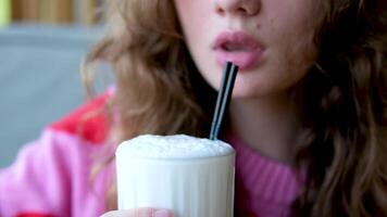 un alegre mujer Bebiendo con hielo latté con un metal Paja en un al aire libre cafetería. video
