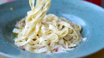 linguini pasta met Carbonara saus Aan een donker achtergrond. Carbonara saus gemaakt van spek, parmezaan, eieren, room en peper. Italiaans voedsel. video