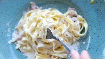 inkompetent flicka wraps spaghetti på en gaffel piatto di deliziosi spaghetti alla carbonara, una tipica ricetta di pasta condita lura una salsa en bas di uova, pecorino e guanciale, cibo italiano video