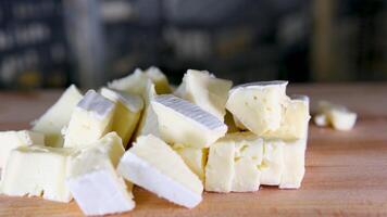 samenstelling van Italiaans kaas, Aan een houten snijdend bord. een hand- duurt de mes en breekt een paar van stukken naar genieten de kwaliteit. video