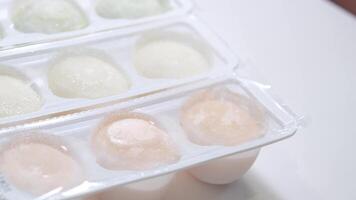 different flavors of Asian dessert mochi, a woman hand takes out sweet ice cream made from peas and rice starch dough from a box onto a white plate video