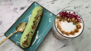 Hot lattes with foam Eclair with pistachios French pastry eclairs with pistachio cream filling covered with green glaze circle rotation close up top view video