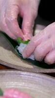 främre skott av en japansk kock förbereder en tallrik av sushi sashimi tallrik med rå fisk i en sushi-bar. närbild på händer. video