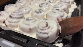 Pouring frosting on Freshly baked cinnamon rolls or Cinnabon close up. Sweet cream cheese frosting pouring on cinnamon rolls. Production of cinnamon rolls. Bakery products. Appetizing cinnamon buns video