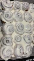 torrencial Crema en recién horneado canela rollos o cinnabon cerca arriba. dulce crema queso Crema torrencial en canela rollos producción de canela rollos panadería productos apetitoso canela bollos video