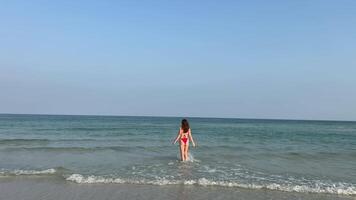 jovem atraente menina fofa vermelho roupa de banho oculos de sol posando e levando uma foto selfie em uma tropical de praia em mar costa. feliz mulher com Smartphone dentro oceano ondas. video