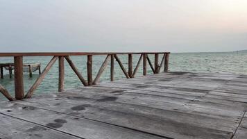 hölzern Ponton auf Wasser. leeren Ponton mit Stroh Regenschirme und Sonnenliegen. Sonne reflektiert im klar Meer Wasser in der Nähe von hölzern Ponton. Sommer- Tag. hölzern Dock Ausdehnung aus in Wasser video