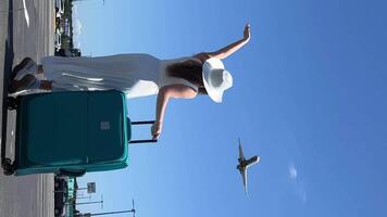ein jung schön Mädchen im ein Weiß Kleid und ein Hut mit ein Koffer Wellen ihr Hand zu ein fliegend Flugzeug Reise Ferien Freude springen haben Spaß Fräulein das Flugzeug eilen zu verlassen ein Neu Chance im Leben video