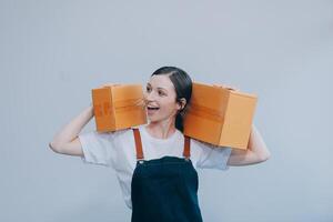 Smiling Asian woman in casual clothes holding a cardboard box mockup while standing against an isolated white background. shipping business concept photo