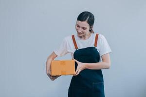 Smiling Asian woman in casual clothes holding a cardboard box mockup while standing against an isolated white background. shipping business concept photo