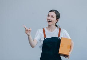 Smiling Asian woman in casual clothes holding a cardboard box mockup while standing against an isolated white background. shipping business concept photo