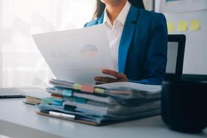 Cheerful business lady working on laptop in office, Asian happy beautiful businesswoman in formal suit work in workplace. Attractive female employee office worker smile. photo