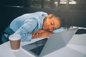 Sad tired young asian lady thinking, sleep at laptop, suffering from overwork, stress in room interior. Deadline, problems in study, work, business, freelance at home new normal with tech photo