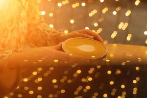 cerca arriba taza de café latté en café tienda.femenina manos participación un taza de café taza con corazón conformado latté Arte espuma en negro madera mesa. foto