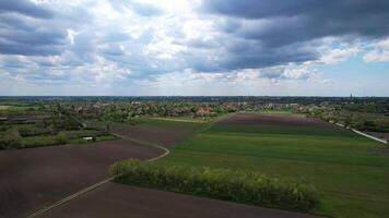 Aerial view of a peaceful rural landscape with agricultural fields under a cloudy sky, suitable for themes like Earth Day and sustainable farming video