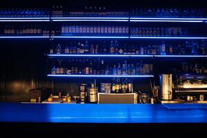 A bar with a blue counter and shelves of liquor. The bar is empty and the lights are on. photo