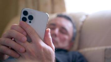 hombre acostado abajo en sofá mientras mirando a su célula teléfono solo a noche video