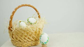 Easter holiday decorative handmade eggs in wicker basket white background space for text embroidery ribbons on eggs ornament blue green yellow color postcard gift congratulations invitation video