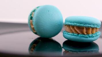 rodopiando azul macaron lavanda ou bru queijo sabor em Preto prato rodopiando delicioso sobremesa restaurante servindo Doçura francês sobremesa almoço chefe de cozinha prato grande quantidade do coberturas amêndoa farinha lento movimento video