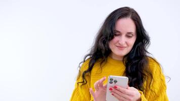 souriant sous le choc content gagner magnifique femme Années 40 ans vieux dans chandail posant isolé sur blanc Contexte dans studio. gens mode de vie concept. Regardez surpris sensationnel tenir en utilisant mobile cellule téléphone video