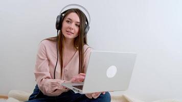 Business woman wearing white headphones doing call at work video