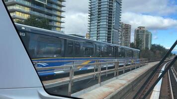 sky train road from Surrey to Vancouver passing trains skyscrapers office buildings science center and other stations from King George to Waterfront real life in a big city british columbia 2023 video