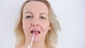 A woman does her own face makeup, applies lipstick and lip gloss. Close-up. The concept of beauty and fashion video