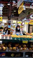 3 les filles dans masques de Asie vendre des légumes et des fruits sur le compteur un vieux femme de retraite âge des promenades passé leur elle regards et feuilles video