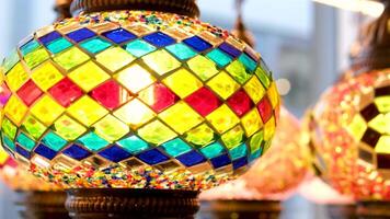 Bright multi-colored Turkish lamps hang in the store shine in different colors mosaic Colored stars and flowers painted on the lamps themselves They look like a light ball video