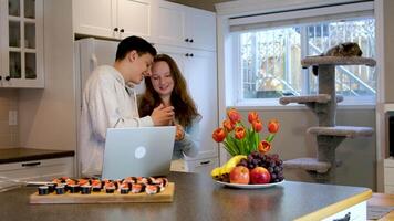 avendo divertimento adolescenziale ragazzo e ragazza Guardando film su computer portatili e mangiare Sushi nel cucina cibo consegna divertimento passatempo piacevole relazione primo Data amici compagne di classe insieme imparare per cucinare asiatico cibo video