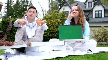 il computer portatile Due adolescente adolescenti mostrando classe Pizza scatola casa consegna picnic compleanno Data Pizza consegna anno Domini ordine in linea veloce cibo estate vacanze trascorrere con amici Là è un' posto per pubblicità testo video