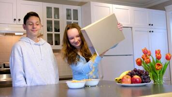 tonåringar Pojkar och flicka matlagning frukost hällde från en låda av flingor på de låda kan ad tömma Plats för text spendera tid tillsammans roligt bror och syster leva i samma hus studenter vänner först kärlek video