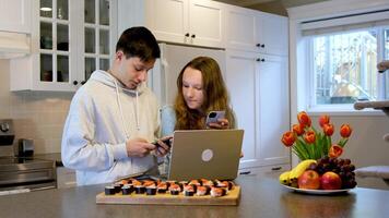 se på bärbar dator mager över fokuserade tror se tonåringar håller på med läxa i de kök beordrade sushi träffa efter skola först datum Kolla på film spendera tid tillsammans pojke flicka 13 14 15 år gammal video