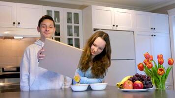 adolescenti ragazzi e ragazza cucinando prima colazione versato a partire dal un' scatola di cereale su il scatola può anno Domini vuoto spazio per testo trascorrere tempo insieme divertimento fratello e sorella vivere nel stesso Casa studenti amici primo amore video