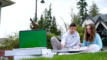 croma chiave il computer portatile con verde schermo picnic su verde erba Aperto scatola con maglieria ago piacevole emozioni divertimento passatempo adolescenti primo Data sedersi pollice su degustazione Pizza delizioso cibo sorpresa gioia video