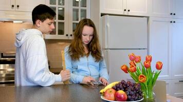 tieners lezen de nieuws Aan de telefoon romantisch jong paar tieners Koken samen in de keuken, hebben een Super goed tijd samen. Mens en vrouw video